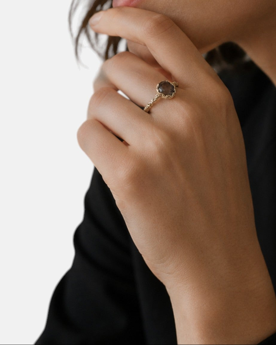 modelo luciendo el anillo Flaminia en la mano, apreciando su tono cálido y brillo elegante sobre la piel.