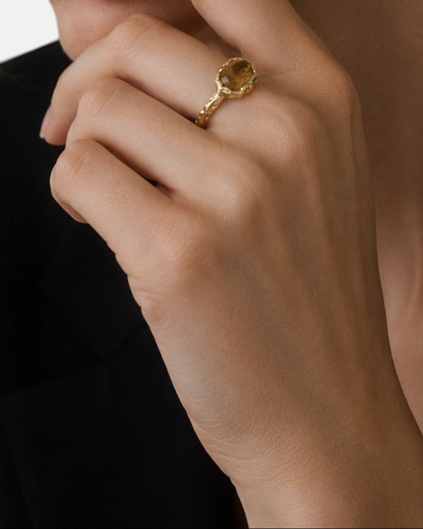 modelo luciendo el anillo Ludovica en la mano, apreciando su calidez dorada y brillo sobre la piel.