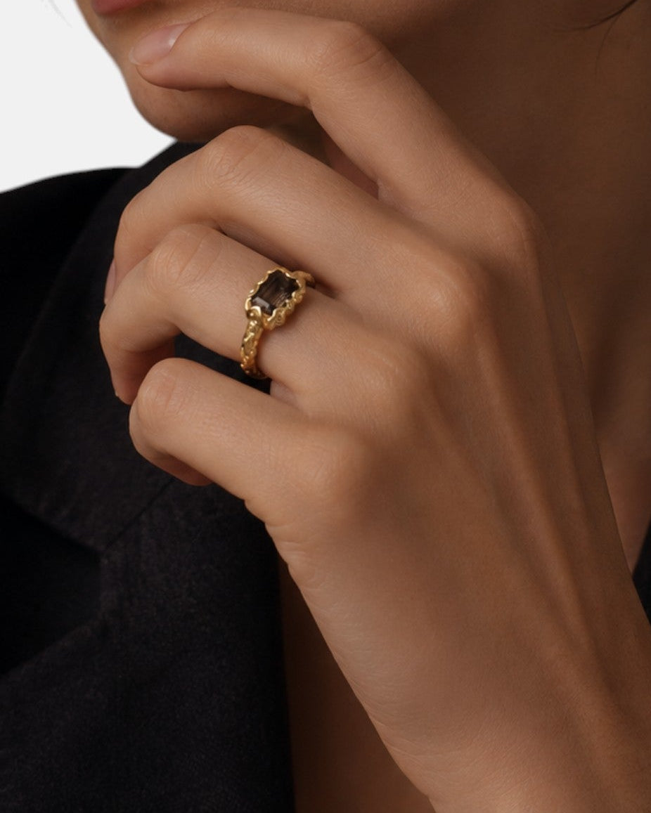 modelo luciendo el anillo Zenobia en la mano, apreciando su corte esmeralda y tono dorado sobre la piel.