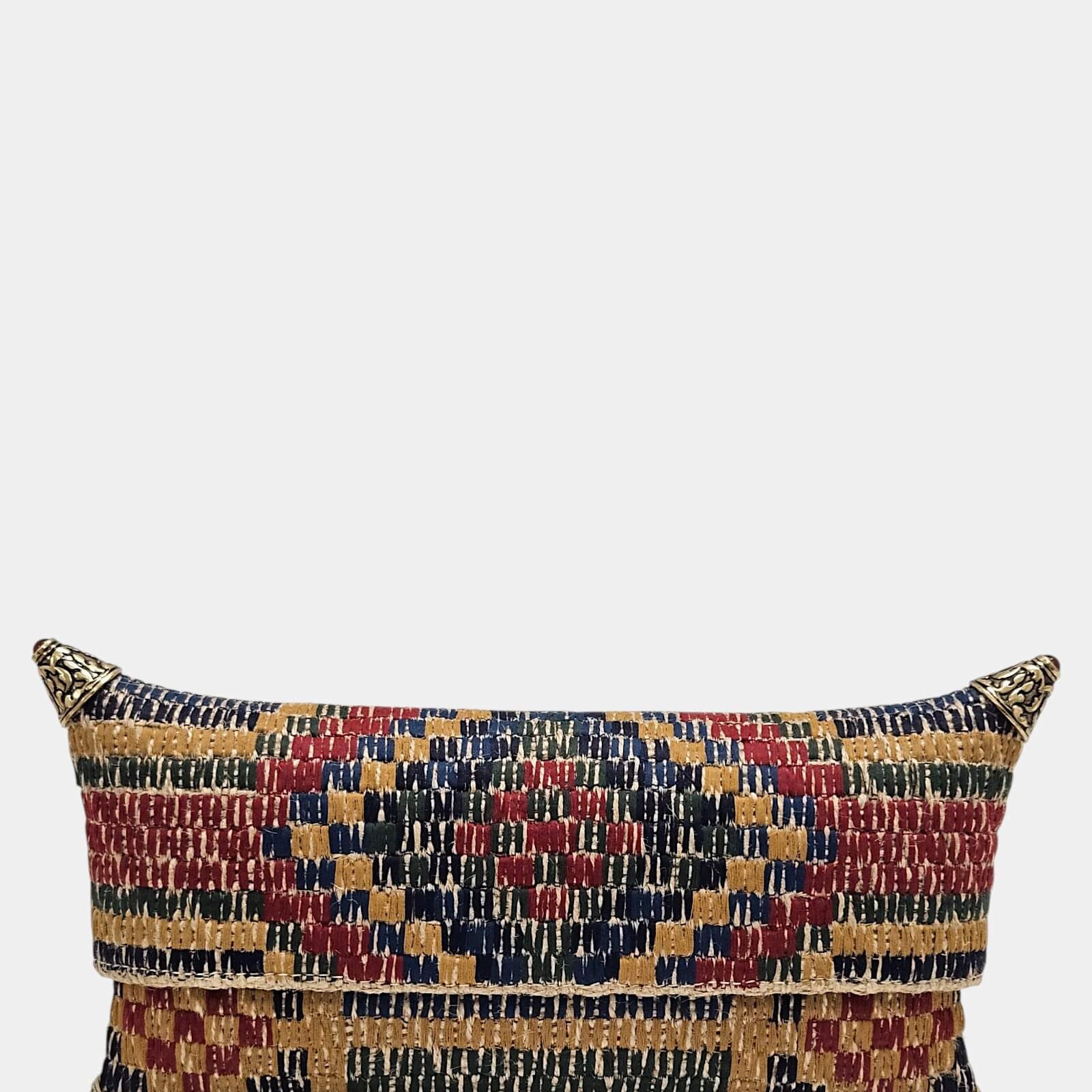 Cartera de mano tipo sobre con patrón de cuadros y franjas étnicas bordadas en hilos de colores, protegida con esquineras metálicas cónicas.