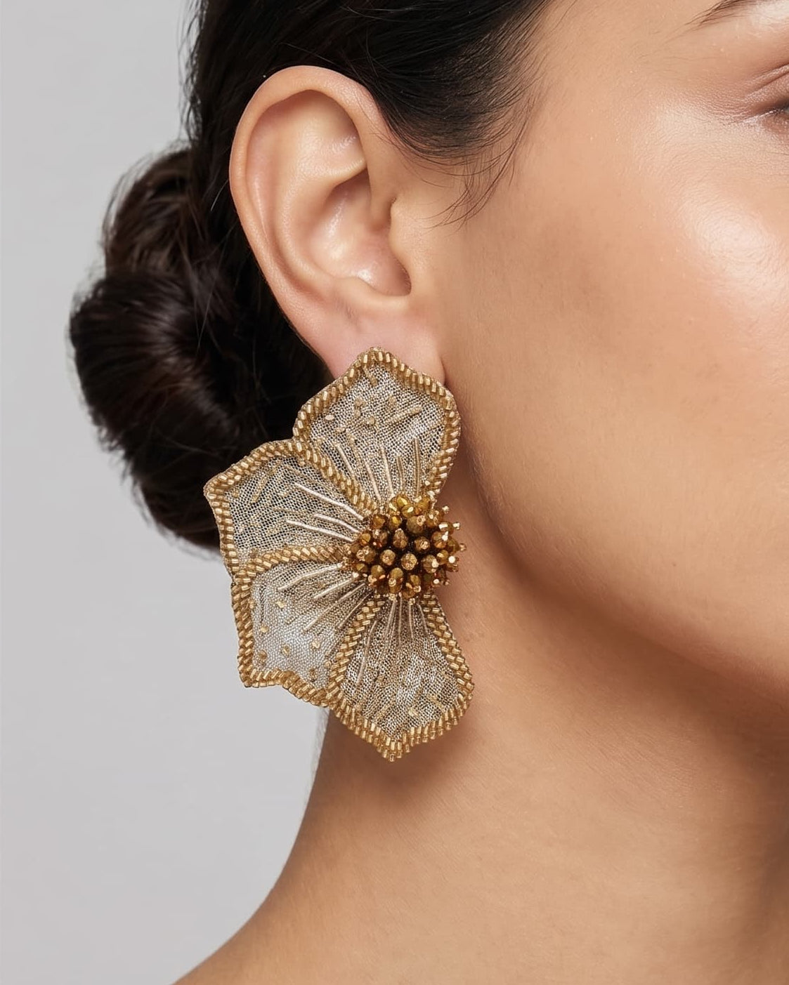 modelo luciendo el pendiente Fleur Dorée et Argent en la oreja, apreciando su silueta en abanico y brillo metálico sobre la piel.