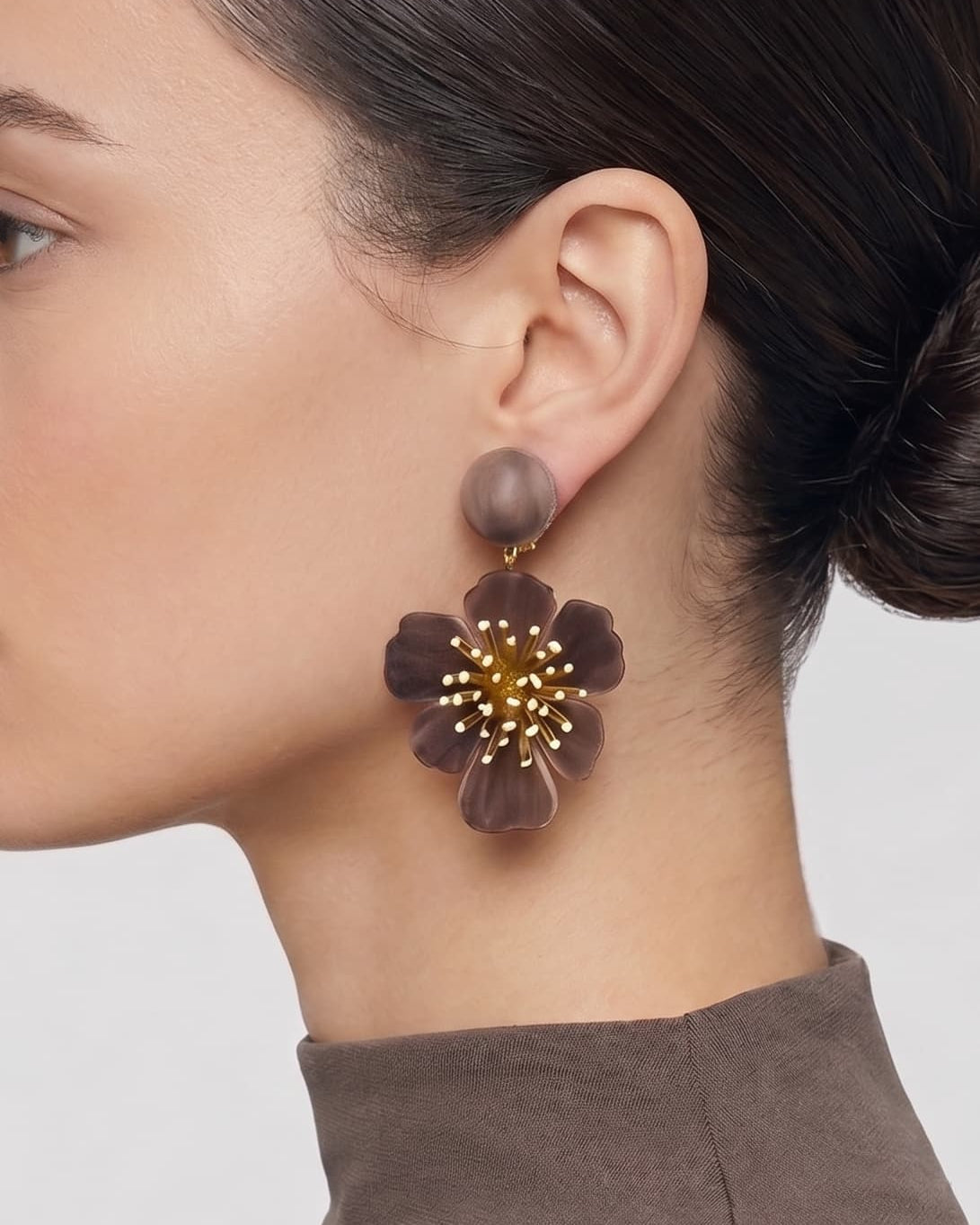 vista de perfil del pendiente de flor marrón de Ciléa Paris colocado en el lóbulo de una modelo, luciendo su caída, su escala maxi de 7.5x4.5 cm y su elegante sistema de cierre de clip.