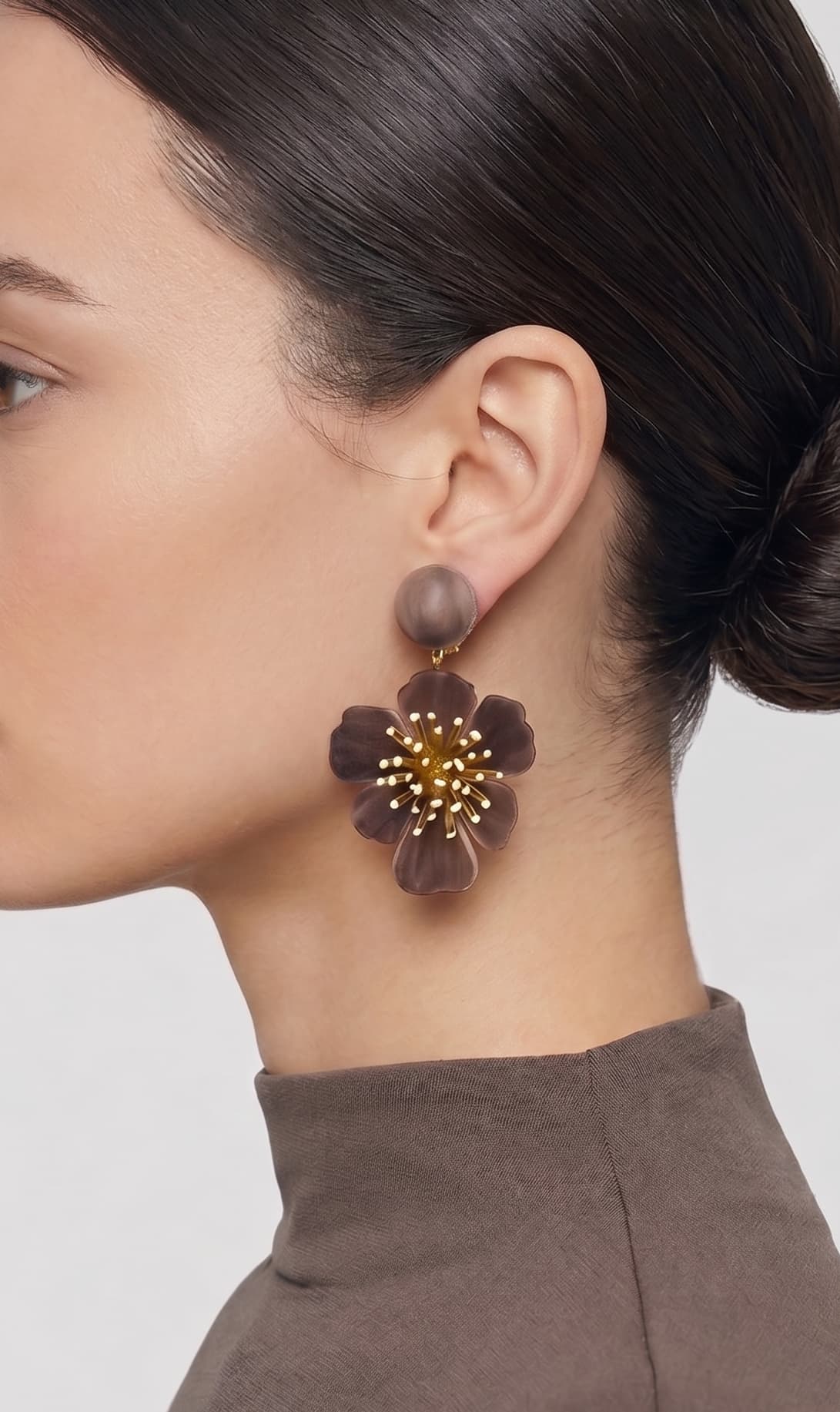 vista de perfil del pendiente de flor marrón de Ciléa Paris colocado en el lóbulo de una modelo, luciendo su caída, su escala maxi de 7.5x4.5 cm y su elegante sistema de cierre de clip.