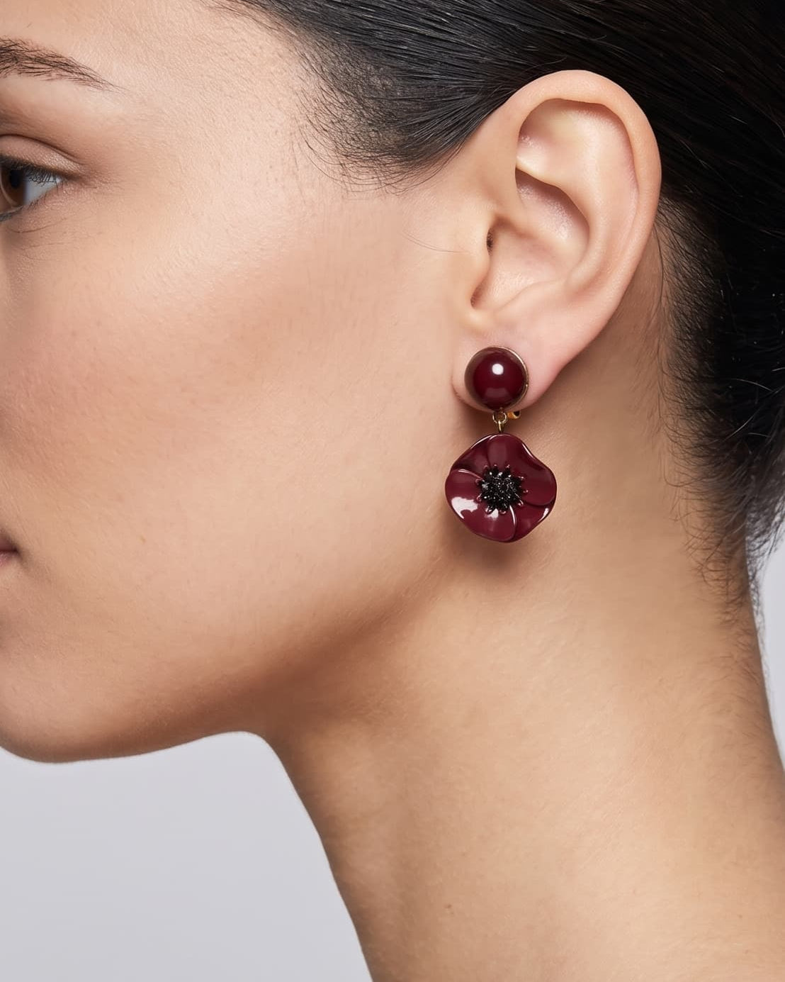 Vista de perfil del pendiente Coquelicot Noir de Ciléa Paris colocado en una modelo, detallando su volumen floral, su intenso tono borgoña y su escala elegante.