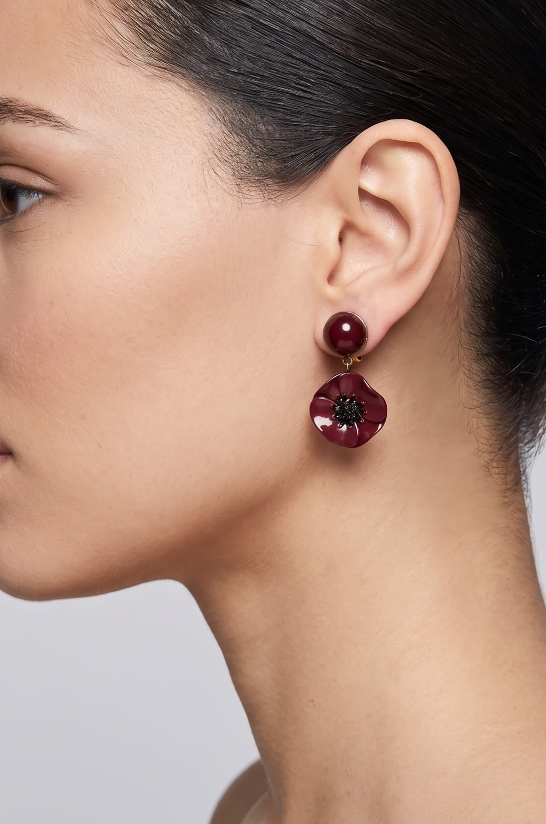 Vista de perfil del pendiente Coquelicot Noir de Ciléa Paris colocado en una modelo, detallando su volumen floral, su intenso tono borgoña y su escala elegante.