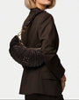 modelo luciendo el bolso Beatrice colgado al hombro sobre un traje oscuro, apreciando su silueta curva y estilo sofisticado.