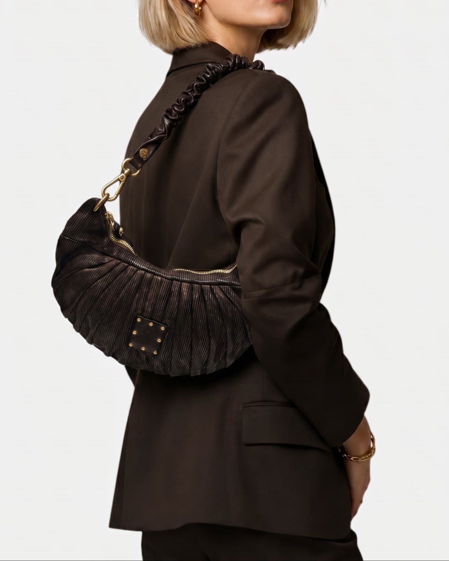 modelo luciendo el bolso Beatrice colgado al hombro sobre un traje oscuro, apreciando su silueta curva y estilo sofisticado.