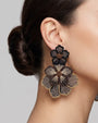 modelo luciendo el pendiente Fleur Double Noire et Dorée en la oreja, apreciando su majestuosa escala XXL sobre la piel.