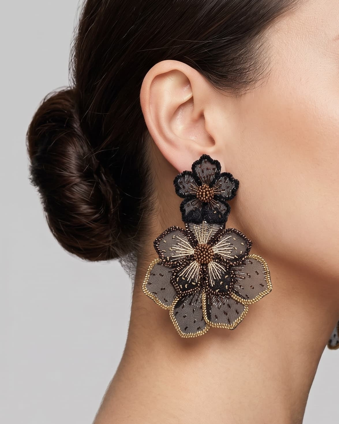 modelo luciendo el pendiente Fleur Double Noire et Dorée en la oreja, apreciando su majestuosa escala XXL sobre la piel.