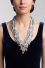 modelo de frente luciendo el collar de Maria Calderara sobre un vestido azul oscuro, permitiendo apreciar la caída alargada de las tiras y el destello de los cristales facetados inferiores.
