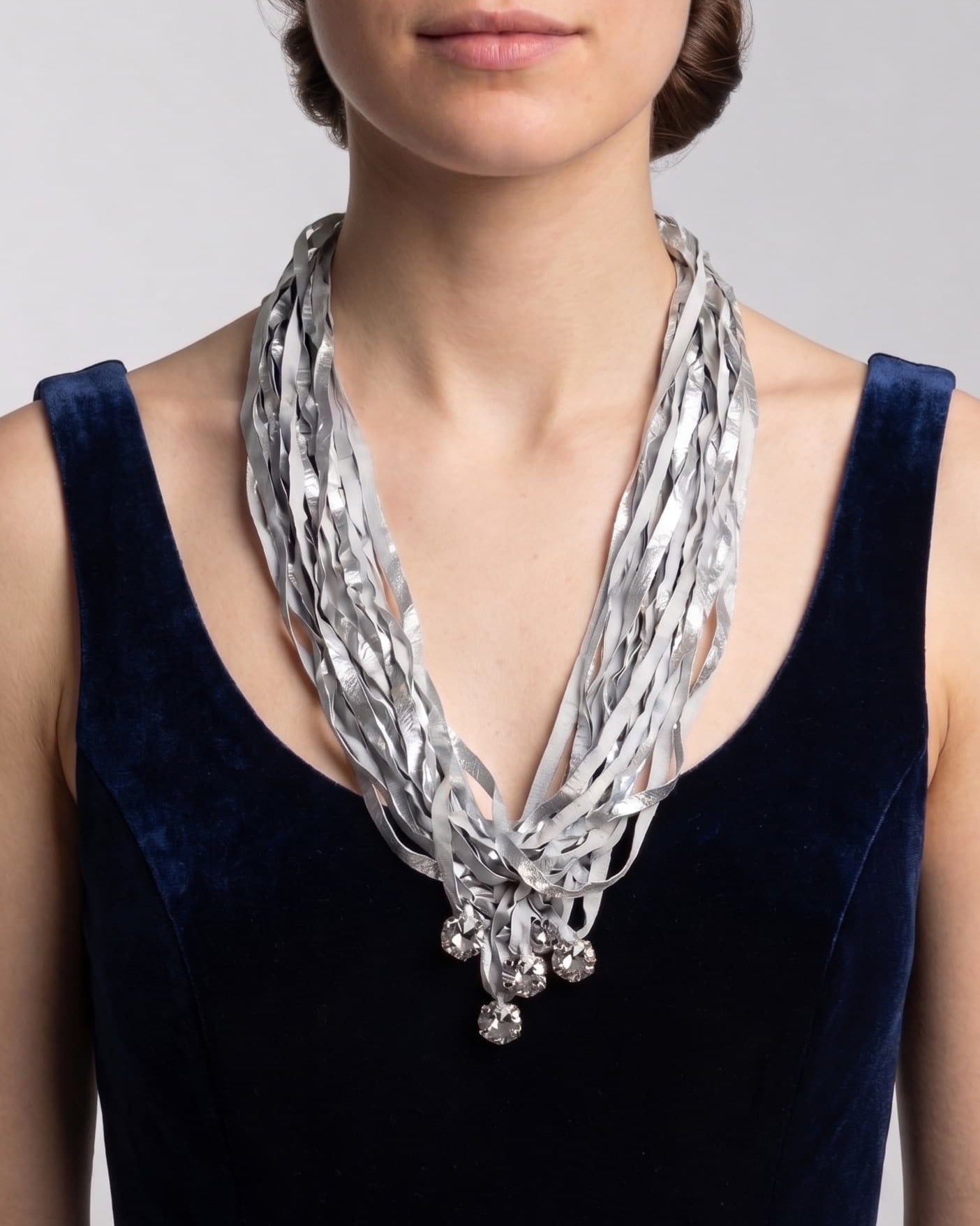 modelo de frente luciendo el collar de Maria Calderara sobre un vestido azul oscuro, permitiendo apreciar la caída alargada de las tiras y el destello de los cristales facetados inferiores.