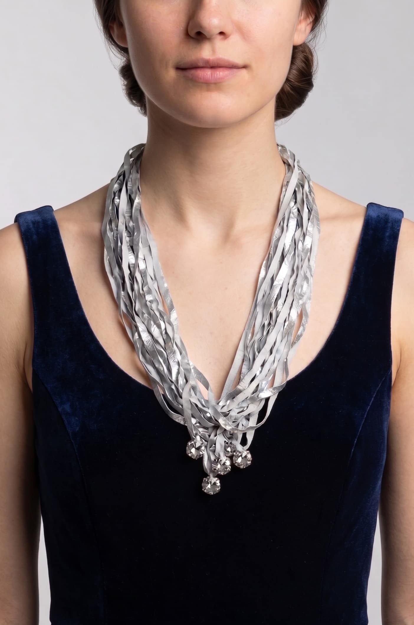 modelo de frente luciendo el collar de Maria Calderara sobre un vestido azul oscuro, permitiendo apreciar la caída alargada de las tiras y el destello de los cristales facetados inferiores.