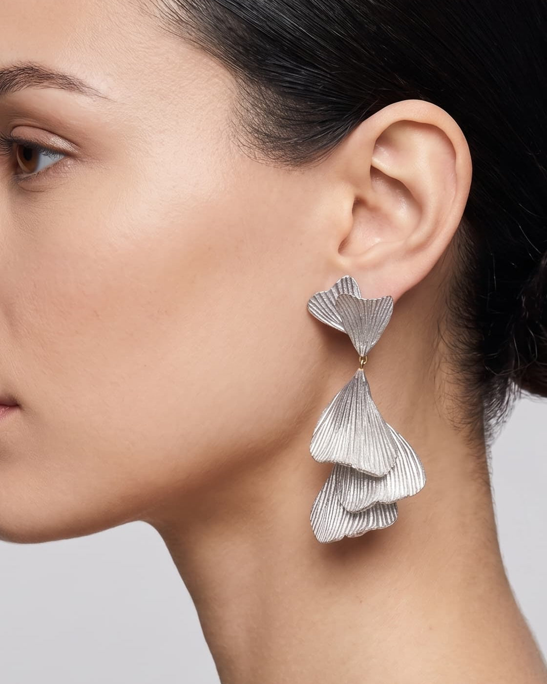 vista de perfil del pendiente plateado de Ciléa Paris colocado en una modelo, detallando su elegante caída, escala extra grande y textura orgánica.