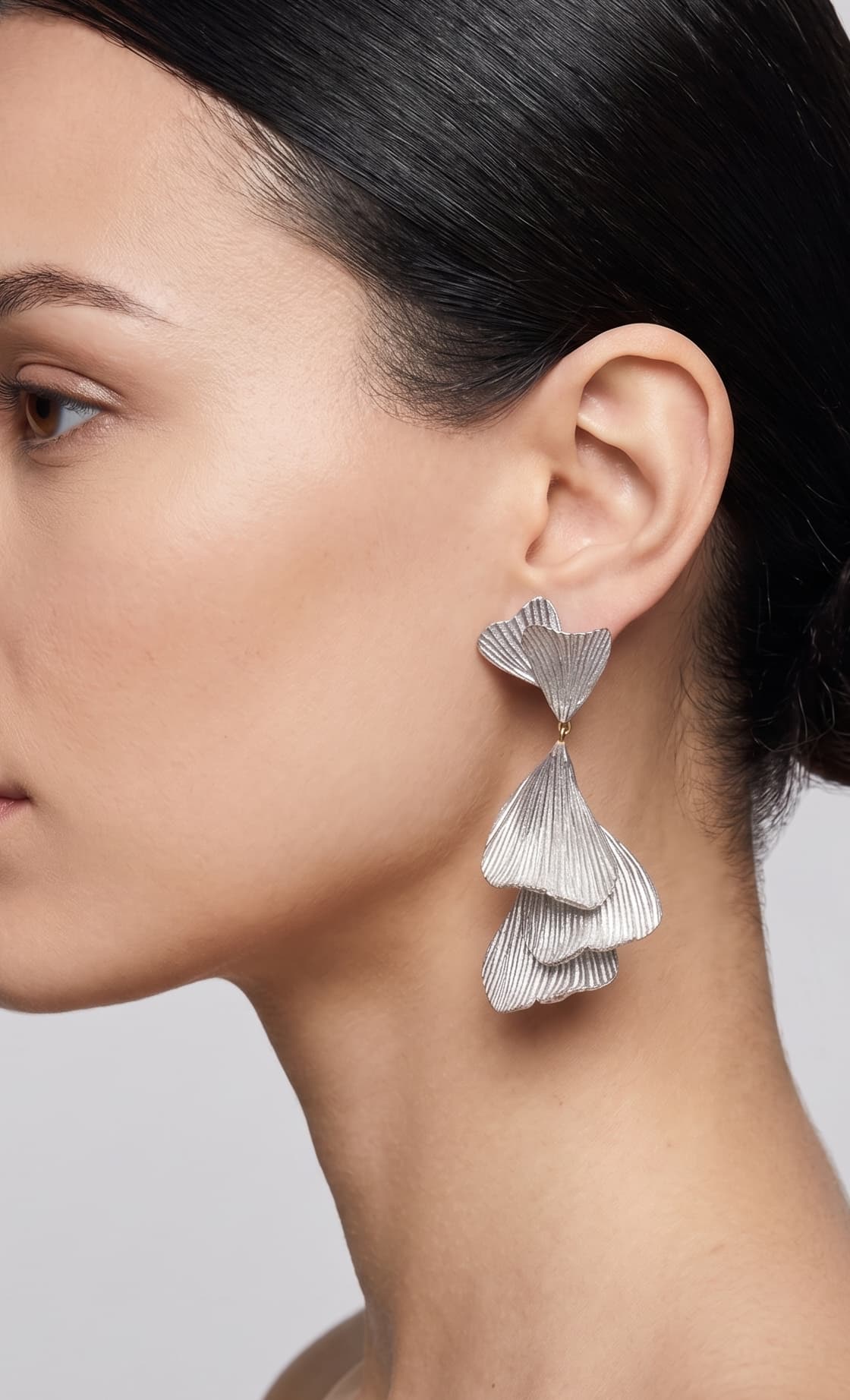 vista de perfil del pendiente plateado de Ciléa Paris colocado en una modelo, detallando su elegante caída, escala extra grande y textura orgánica.