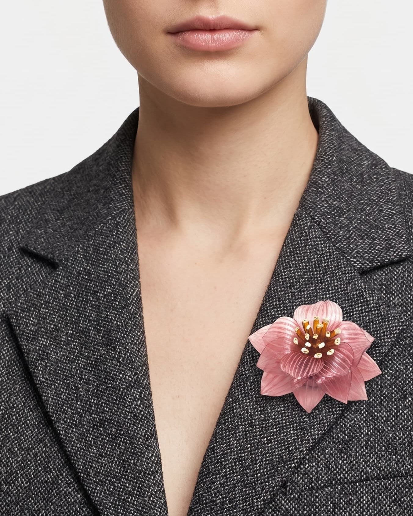 modelo de frente portando el broche maxi de loto rosa prendido en la solapa de una blazer de sastre gris marengo, mostrando su escala elegante.