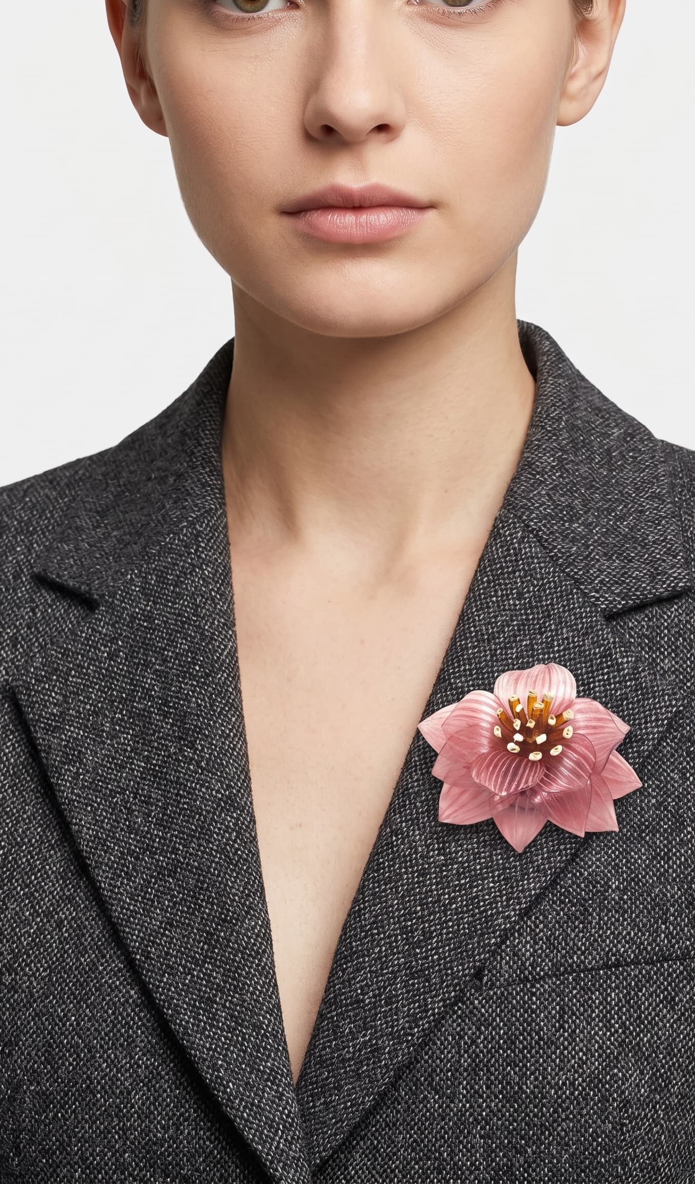 modelo de frente portando el broche maxi de loto rosa prendido en la solapa de una blazer de sastre gris marengo, mostrando su escala elegante.