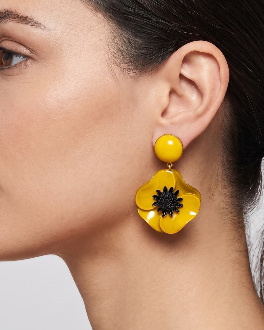 vista de perfil del pendiente de amapola amarillo de Ciléa Paris colocado en una modelo, detallando su volumen floral y su escala elegante.