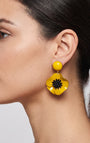 vista de perfil del pendiente de amapola amarillo de Ciléa Paris colocado en una modelo, detallando su volumen floral y su escala elegante.