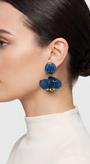 vista de perfil del pendiente de flor azul de Ciléa Paris colocado en el lóbulo de una modelo, detallando su caída, su escala estilizada de 5.5x4.5 cm y su sujeción de clip.