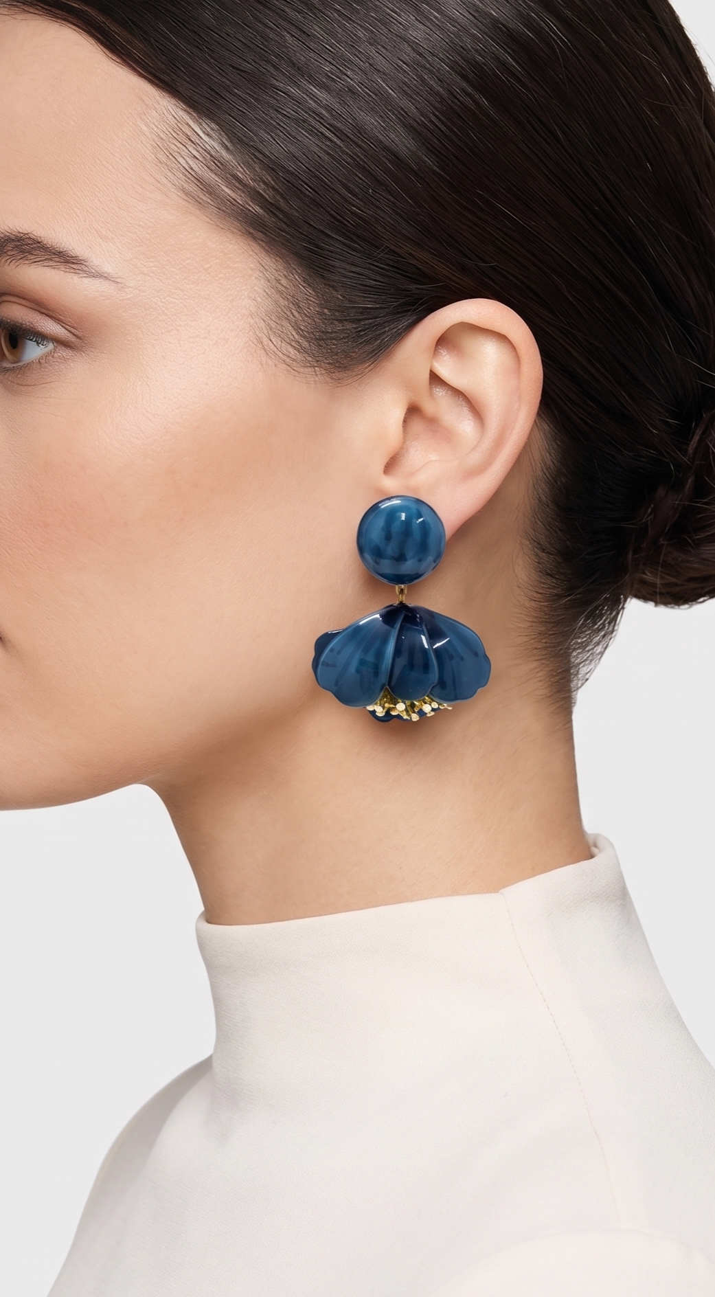 vista de perfil del pendiente de flor azul de Ciléa Paris colocado en el lóbulo de una modelo, detallando su caída, su escala estilizada de 5.5x4.5 cm y su sujeción de clip.