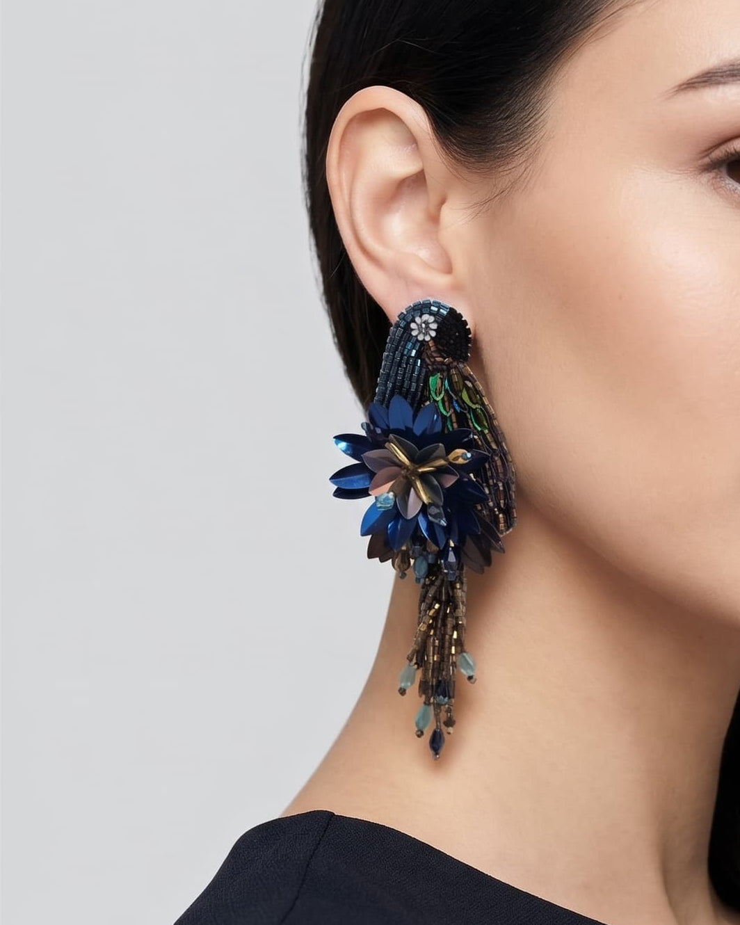 modelo luciendo el pendiente Perroquet Bleu en la oreja, apreciando su silueta de ave, volumen floral y escala sobre la piel.