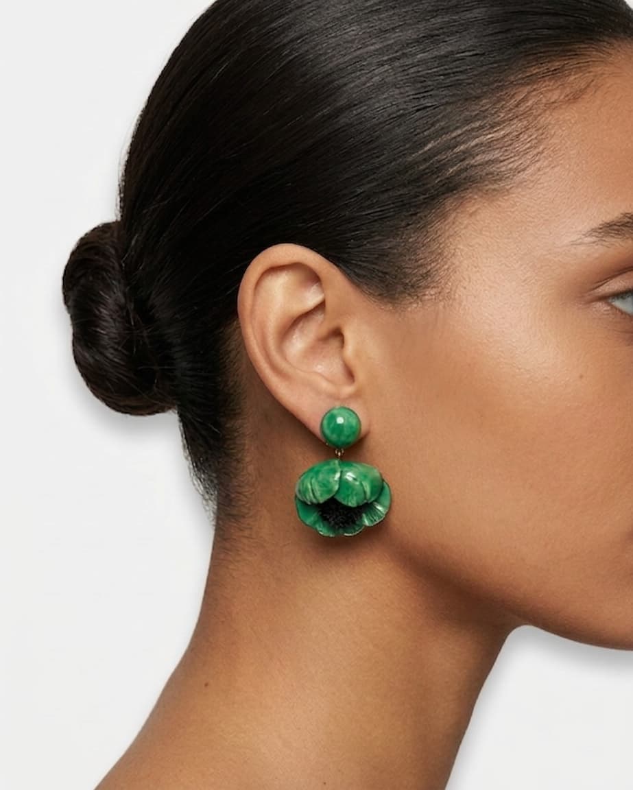 modelo luciendo el pendiente colgante de amapola verde, apreciando su escala maximalista, su relieve tridimensional y cómo adorna el rostro con sofisticación.