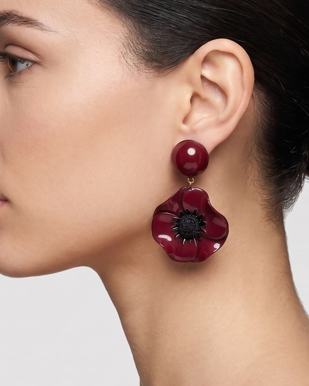 vista de perfil del pendiente de amapola borgoña de Ciléa Paris colocado en una modelo, detallando su volumen floral, su brillo esmaltado y su escala elegante.