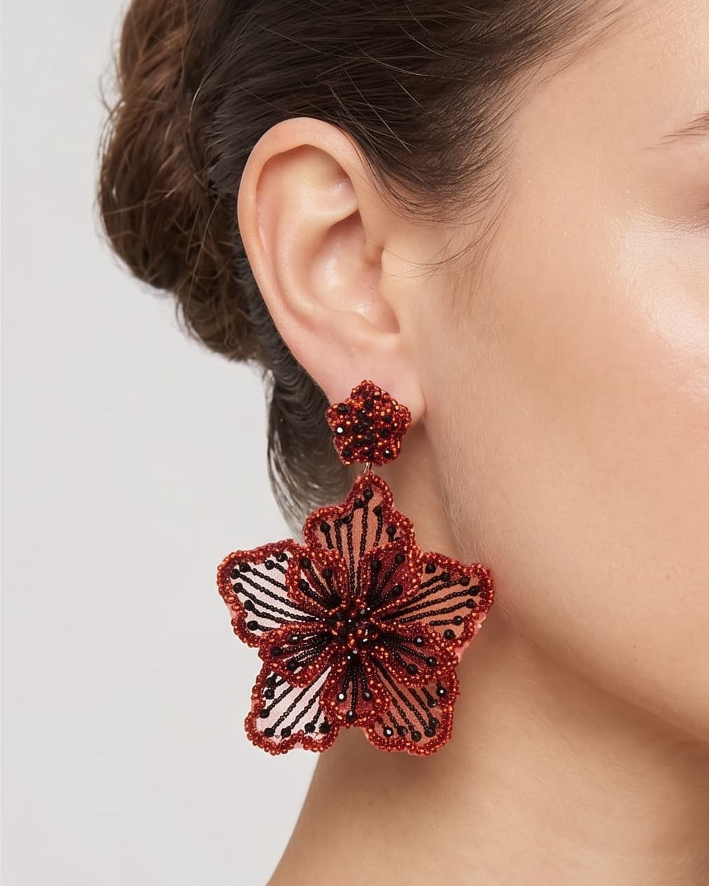 modelo luciendo el pendiente Fleur Terracota en la oreja, apreciando su silueta maxi y volumen floral sobre la piel.