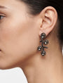 Detalle de los pendientes "Brote de Medianoche" puestos, destacando su silueta orgánica y el brillo oscuro.