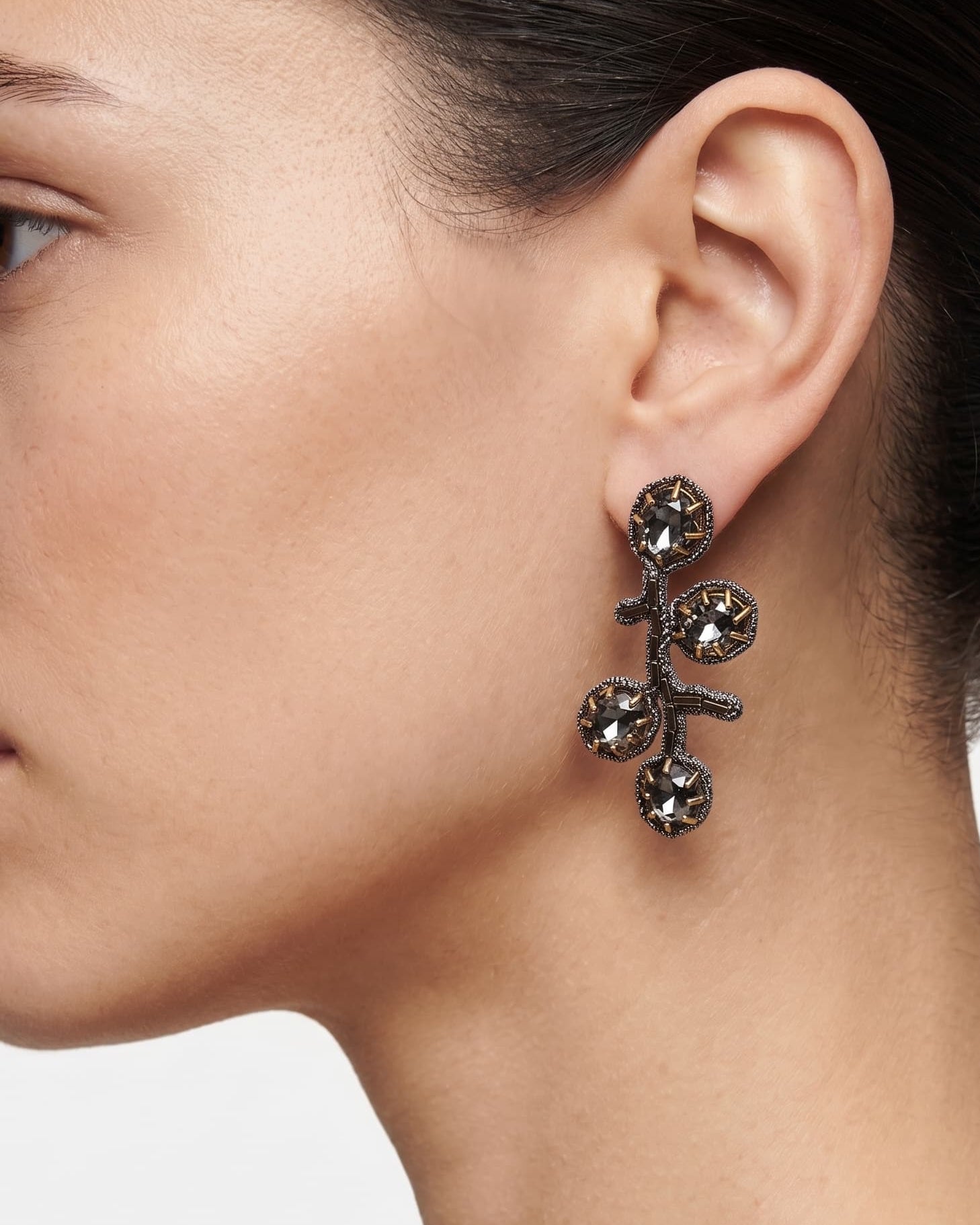 Detalle de los pendientes "Brote de Medianoche" puestos, destacando su silueta orgánica y el brillo oscuro.