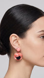 modelo luciendo el pendiente colgante de amapola rosa, apreciando su escala maximalista, su relieve tridimensional y cómo adorna el rostro con sofisticación.