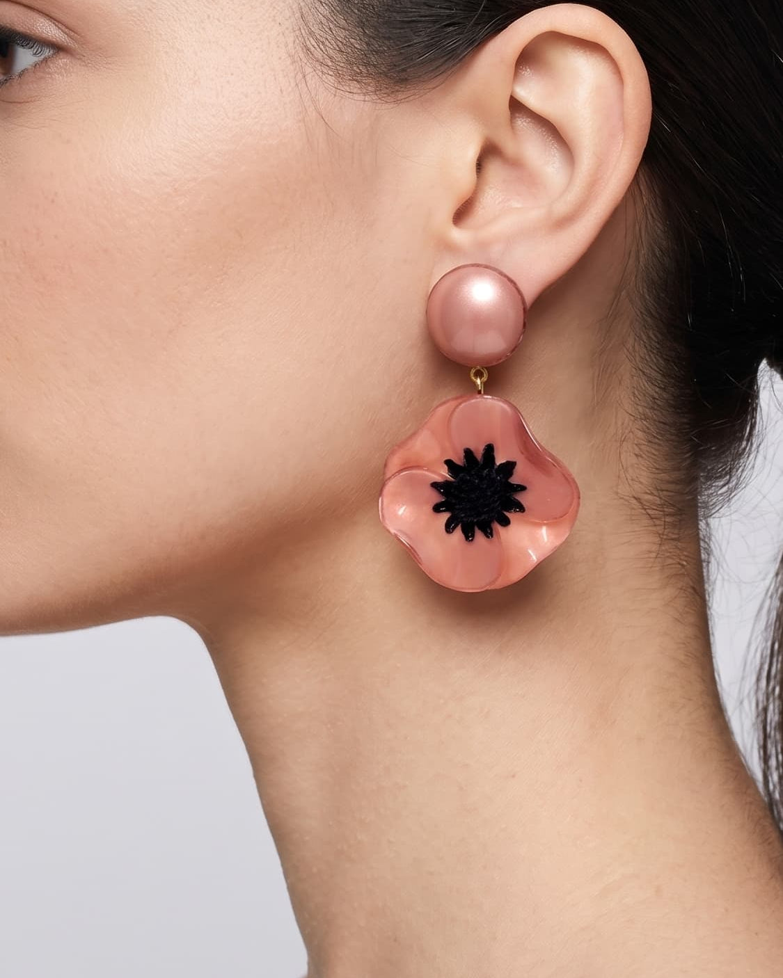 vista de perfil del pendiente de amapola rosa de Ciléa Paris colocado en una modelo, detallando su volumen floral y su escala elegante.