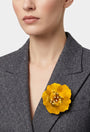 vista frontal del broche de flor de Ciléa Paris colocado en la solapa de una chaqueta de sastre gris, detallando su escala maxi y su elegancia luminosa.