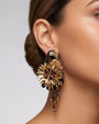 modelo luciendo el pendiente Perroquet en la oreja, apreciando su silueta de ave, volumen floral y escala sobre la piel.