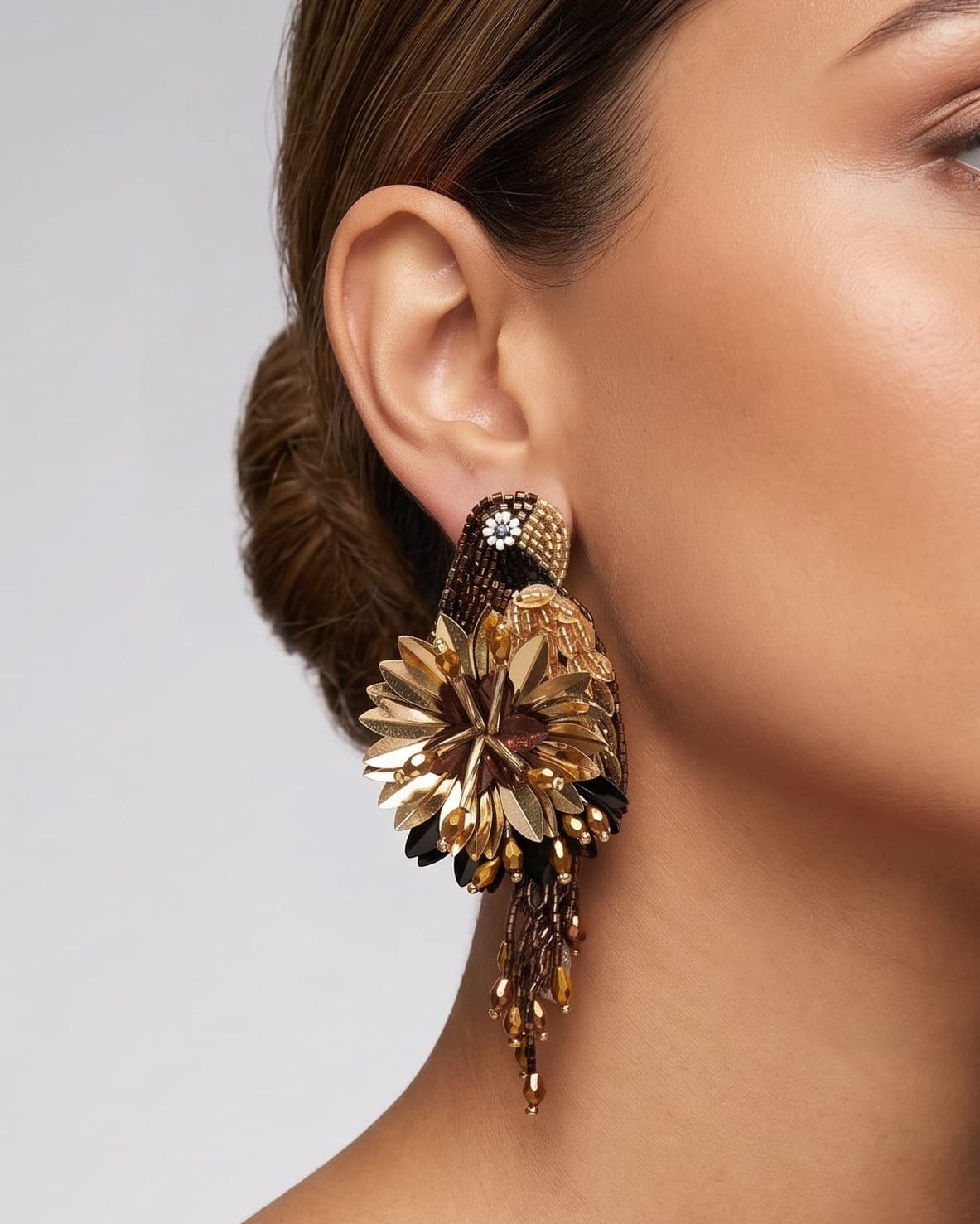 modelo luciendo el pendiente Perroquet en la oreja, apreciando su silueta de ave, volumen floral y escala sobre la piel.