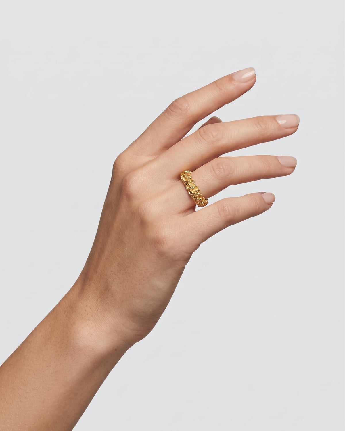 modelo luciendo el anillo Anello Fascia Dorata de Maria e Luisa en la mano, apreciando su acabado dorado y delicada escala sobre la piel.