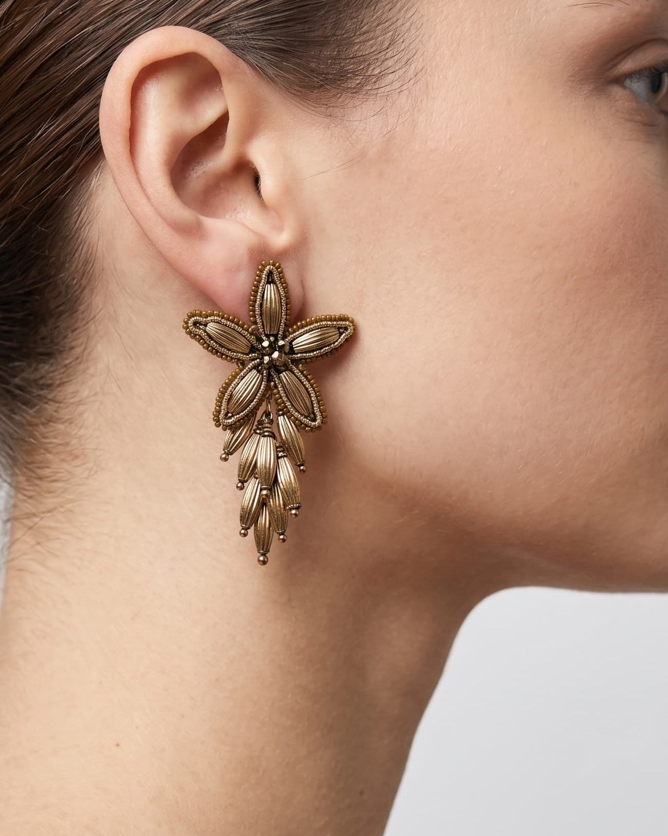 Mujer luciendo los pendientes "Flor de Invierno", destacando su diseño articulado y el acabado en bronce.