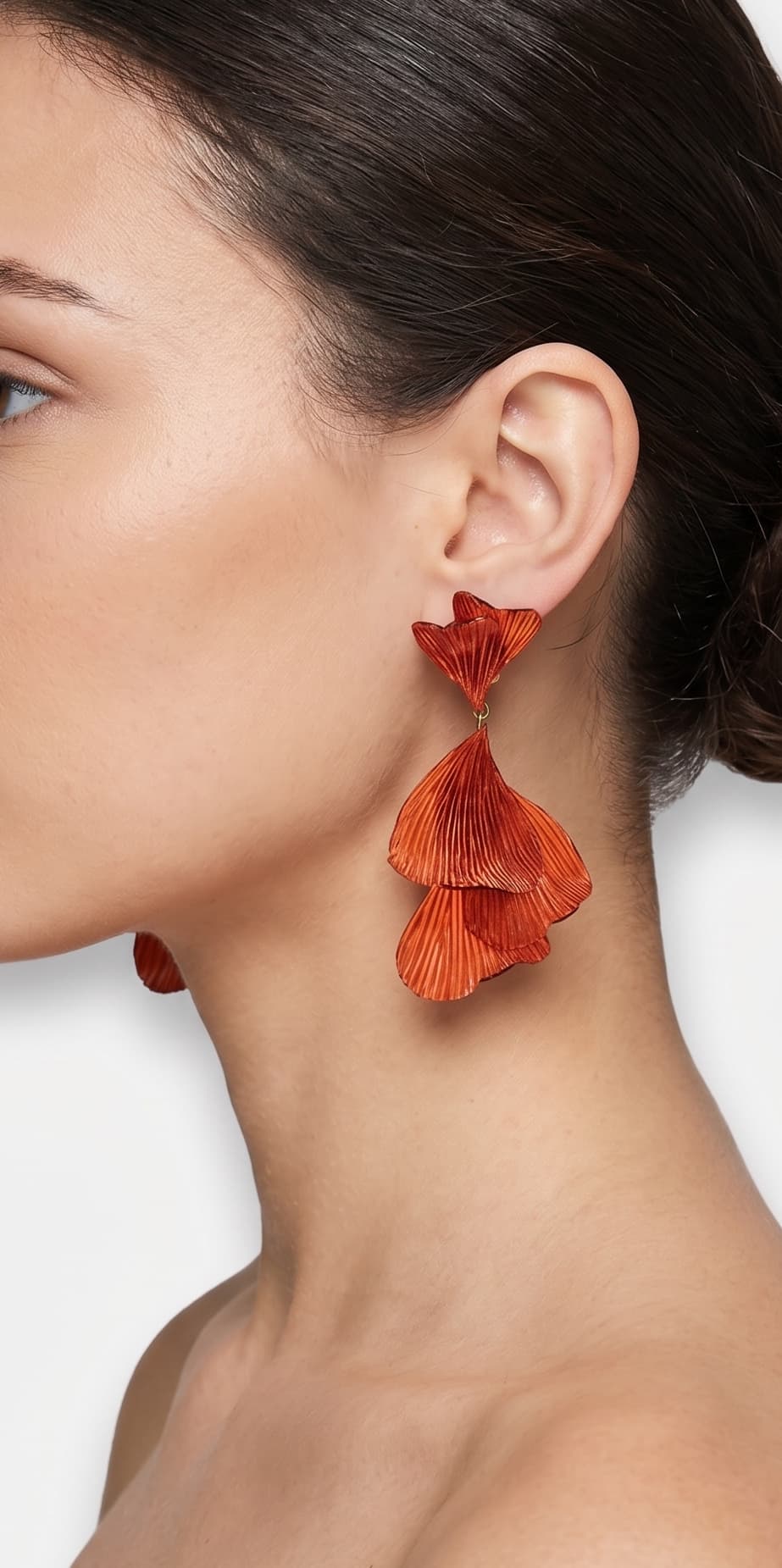 vista de perfil del pendiente de hojas ginkgo color teja de Ciléa Paris colocado en el lóbulo de una modelo, resaltando su caída fluida, su escala maxi de 9x4.5 cm y su sujeción de perno con tuerca.