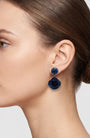 Vista de perfil del pendiente de amapola azul de Ciléa Paris colocado en una modelo, detallando su volumen floral, su tono profundo y su escala elegante.