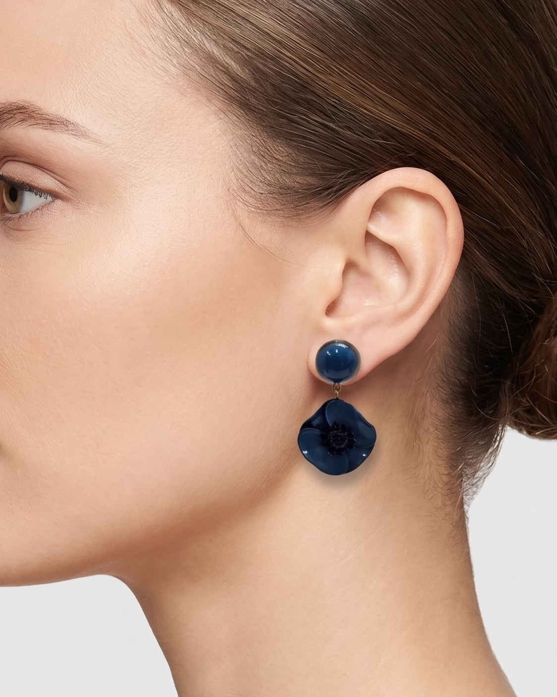 Vista de perfil del pendiente de amapola azul de Ciléa Paris colocado en una modelo, detallando su volumen floral, su tono profundo y su escala elegante.