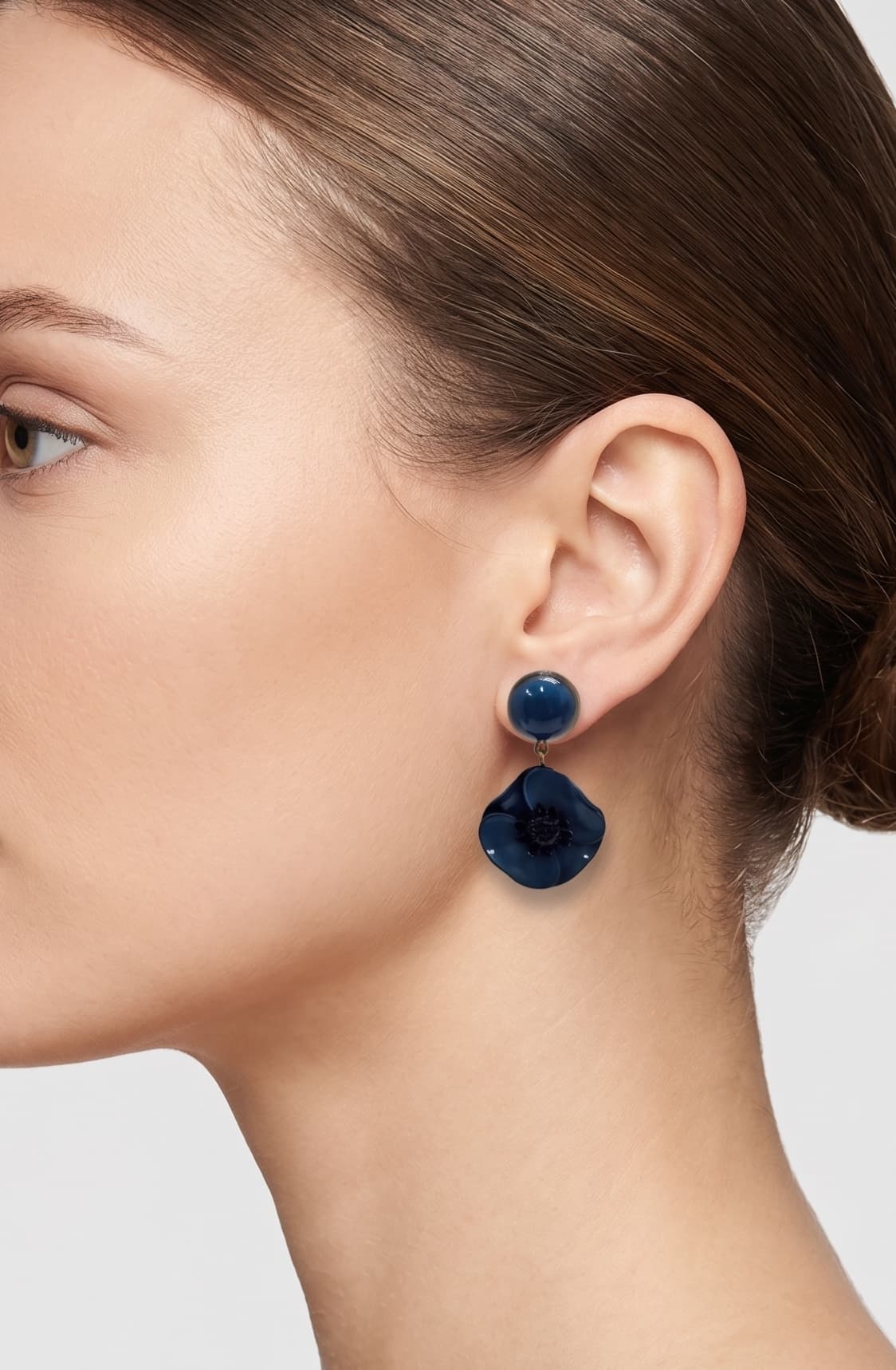 Vista de perfil del pendiente de amapola azul de Ciléa Paris colocado en una modelo, detallando su volumen floral, su tono profundo y su escala elegante.