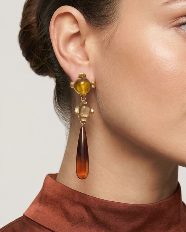 modelo luciendo el pendiente Ambre Caída en la oreja, apreciando su silueta estilizada y tono cálido sobre la piel.