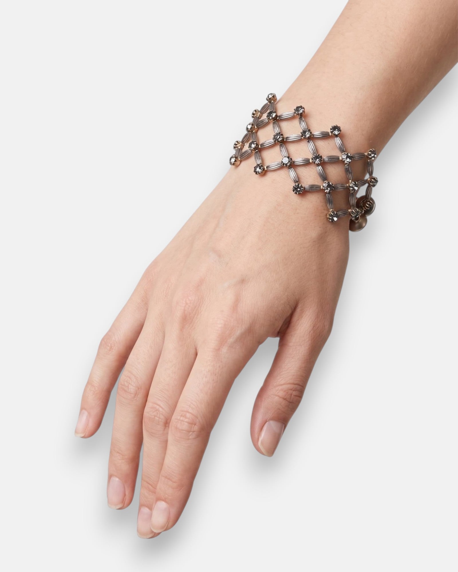 Vista del brazalete de rejilla "Red de Luces Ahumada" en la muñeca, mostrando su transparencia calada y formato ancho.