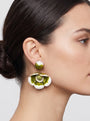 modelo luciendo el pendiente colgante de flor verde y blanca, apreciando su escala maximalista, su relieve tridimensional y cómo adorna el rostro con sofisticación.