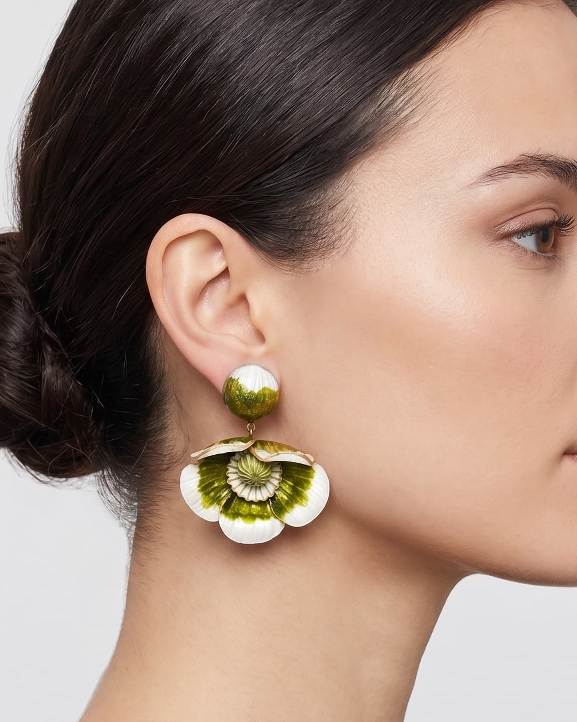modelo luciendo el pendiente colgante de flor verde y blanca, apreciando su escala maximalista, su relieve tridimensional y cómo adorna el rostro con sofisticación.