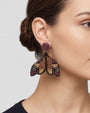 modelo luciendo el pendiente Papillon de Nuit Violet et Bronze en la oreja, apreciando su silueta de alas desplegadas y volumen sobre la piel.