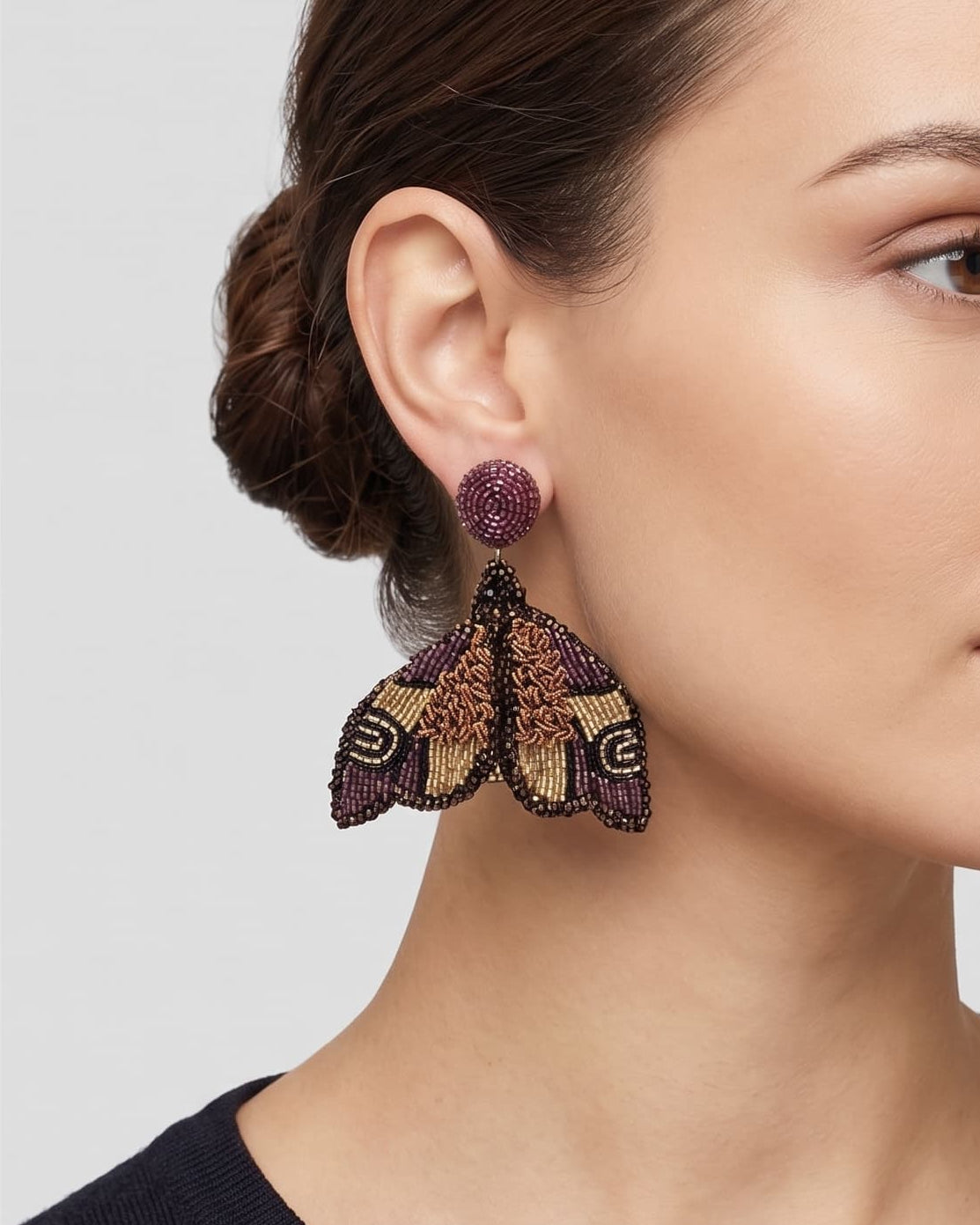 modelo luciendo el pendiente Papillon de Nuit Violet et Bronze en la oreja, apreciando su silueta de alas desplegadas y volumen sobre la piel.