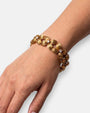 Mujer luciendo la pulsera "Guirnalda Áurea", destacando su volumen escultórico y brillo dorado en la muñeca.