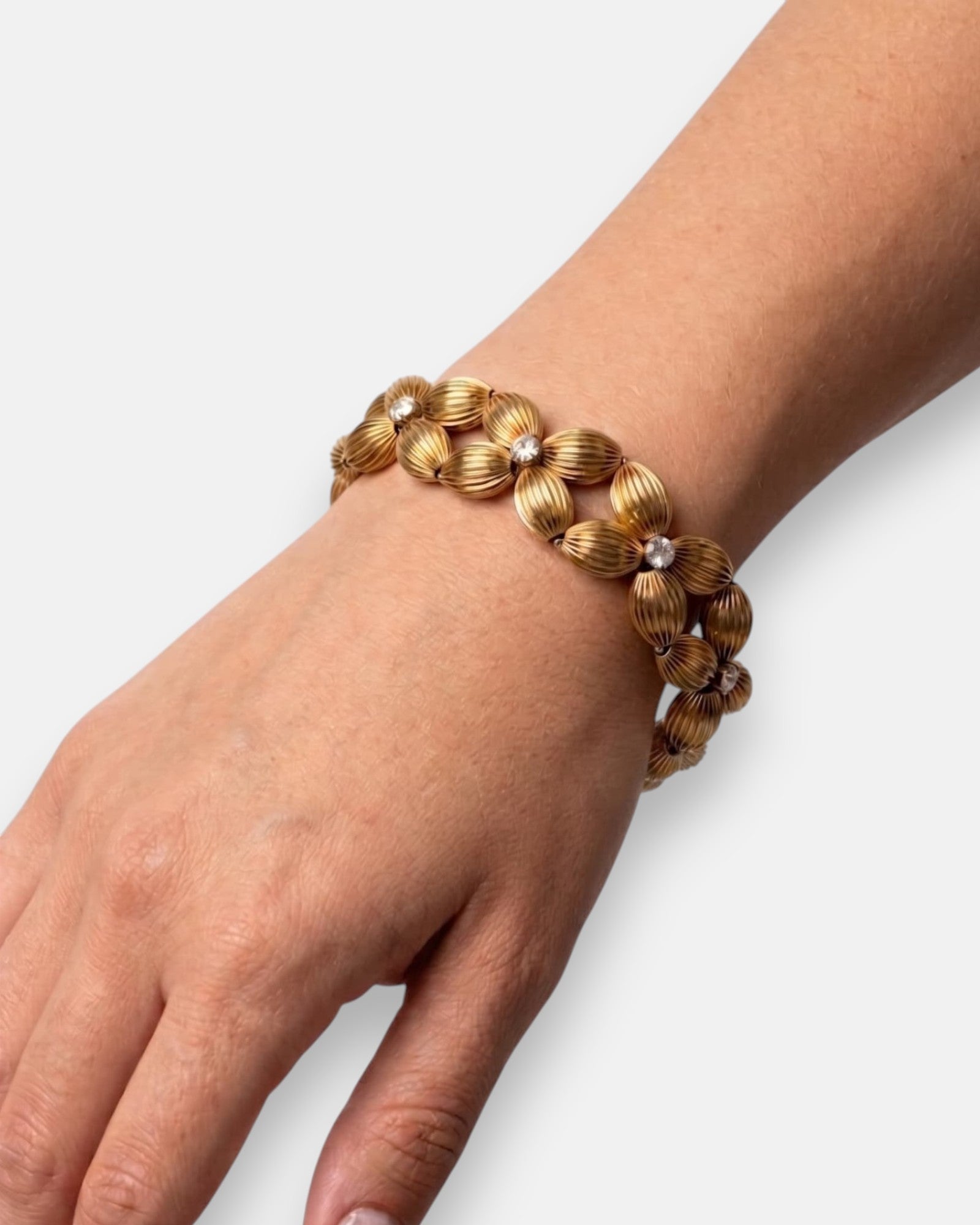 Mujer luciendo la pulsera "Guirnalda Áurea", destacando su volumen escultórico y brillo dorado en la muñeca.