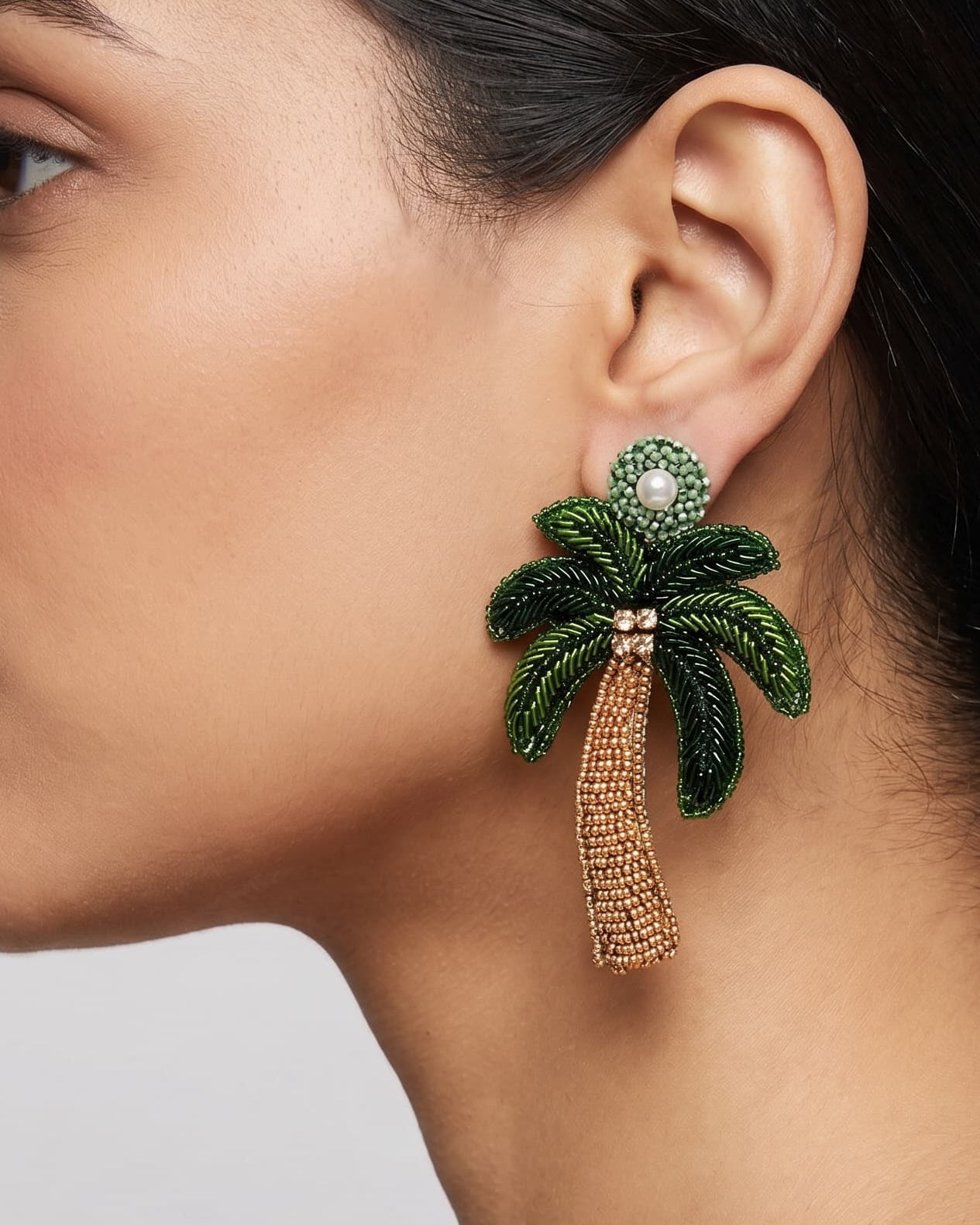 Primer plano lateral de mujer luciendo los pendientes "Oasis Tropical", resaltando su diseño vertical y el detalle de la perla.